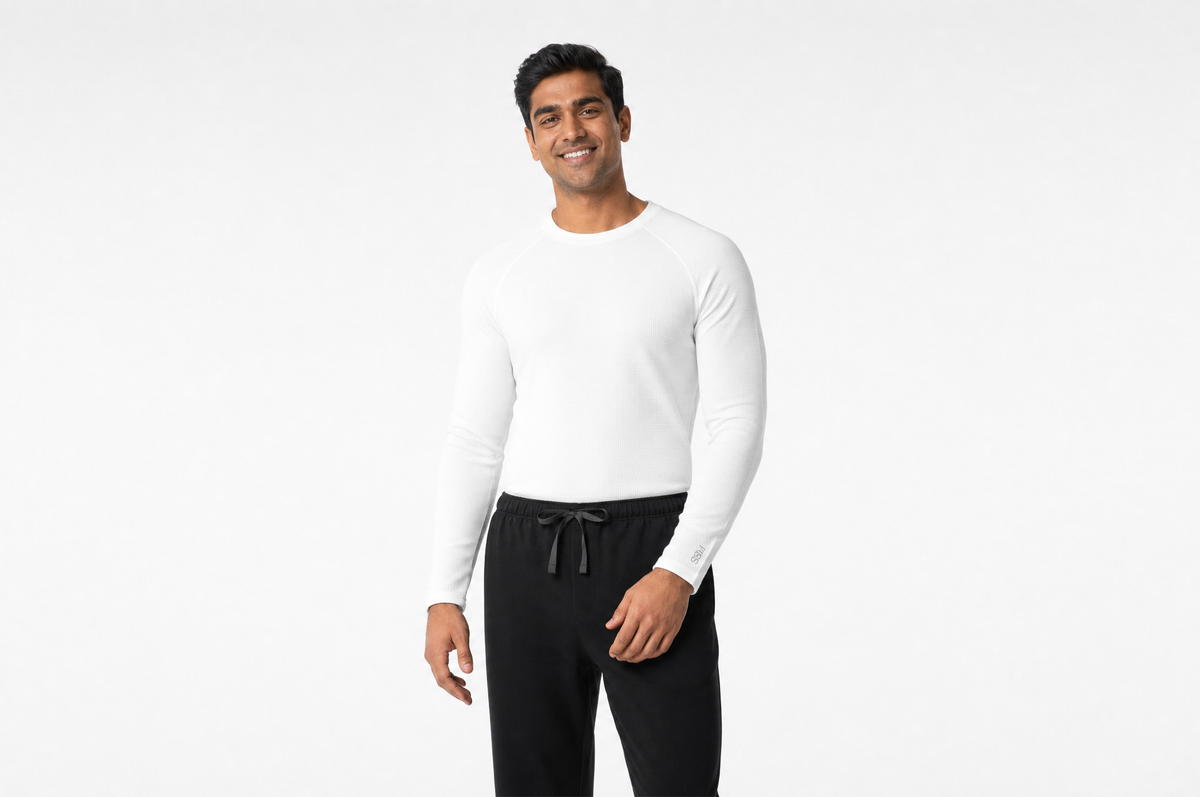 Man wearing a white long-sleeve underscrub top and black scrub pants with a drawstring waist, standing against a plain white background.