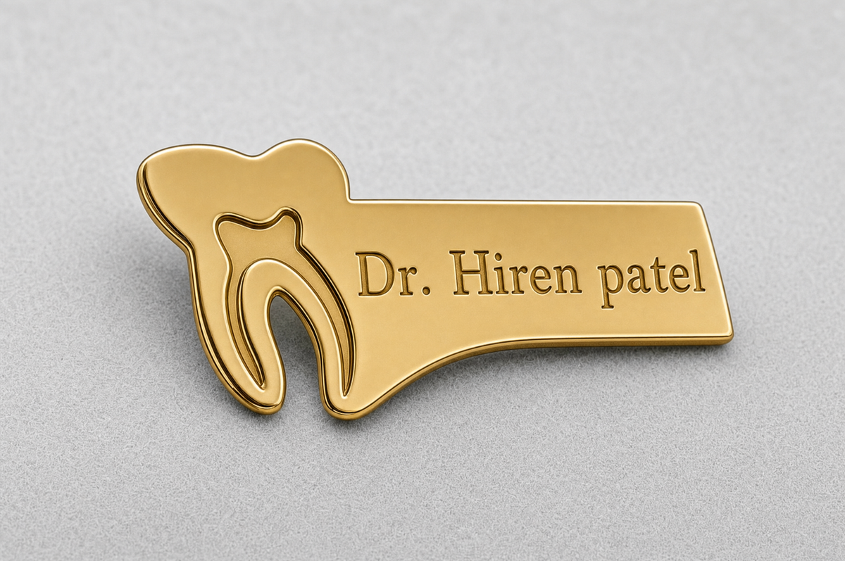Gold tooth-shaped personalised doctor brooch with engraved “Dr. Hiren patel” nameplate.