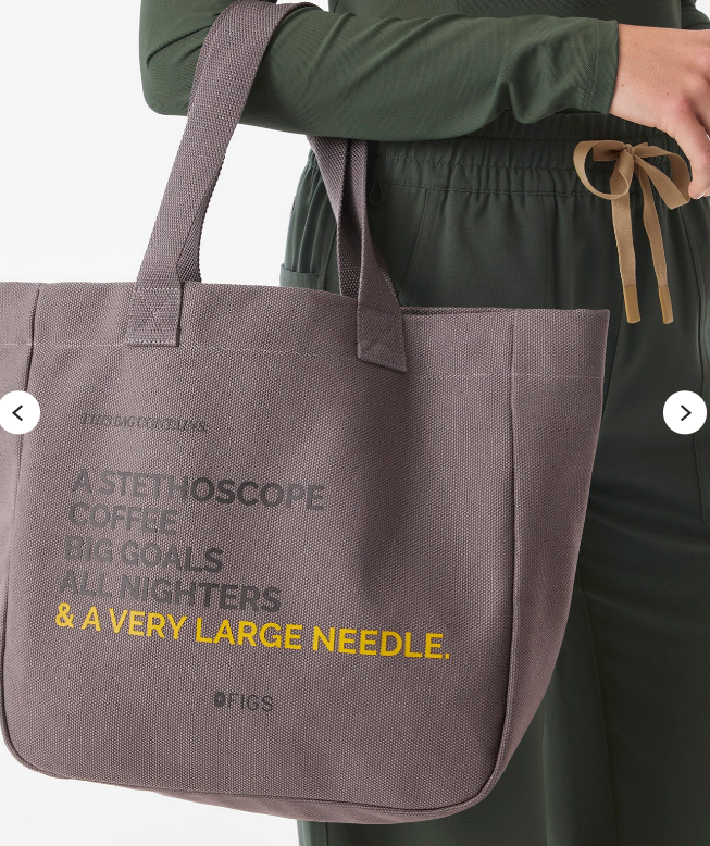 Woman wearing dark green medical scrubs and carrying a taupe-grey tote bag with medical-themed lettering in grey and yellow.