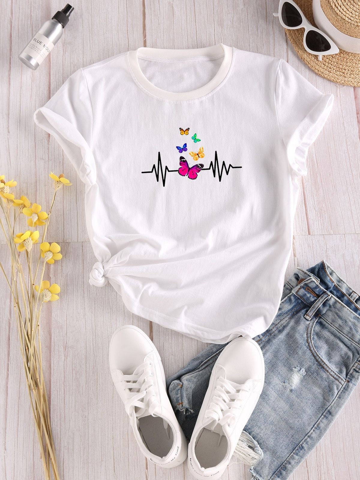 White women’s graphic T-shirt featuring a black ECG heartbeat line with colourful butterfly illustrations across the chest.